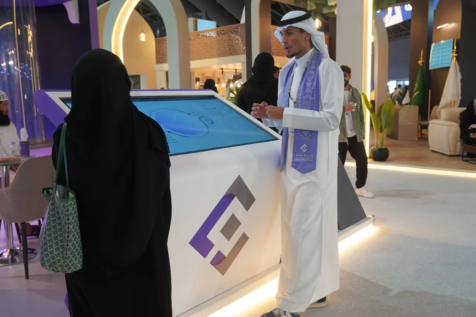 مضيف يشرح لزائرة عبر شاشة لمس تفاعلية داخل جناح من تنفيذ الرؤية العميقة